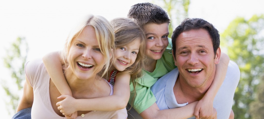 Couple giving two young children piggyback rides smiling